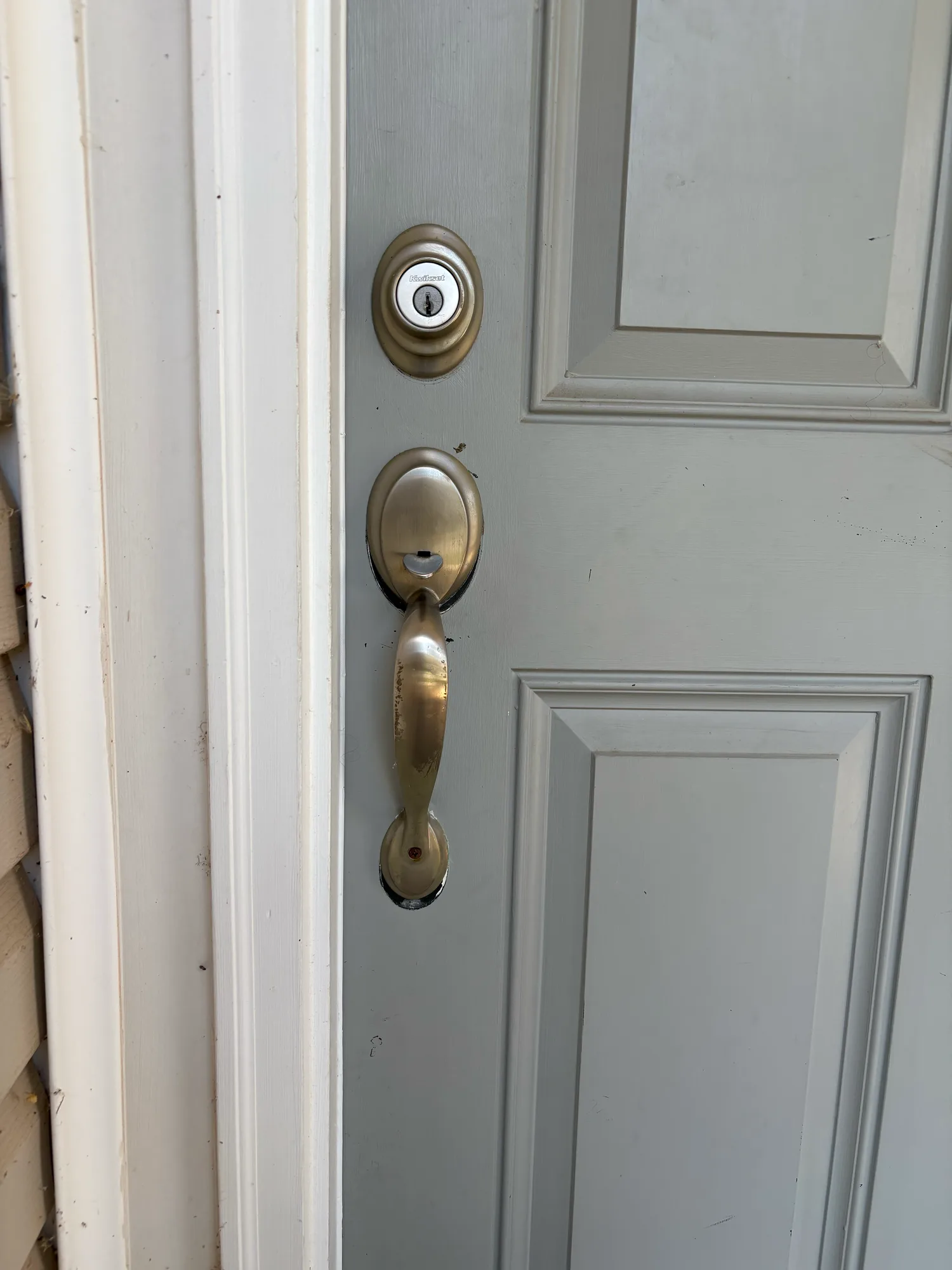 A Kwikset handleset and deadbolt on the front door of a house, seen from outside
